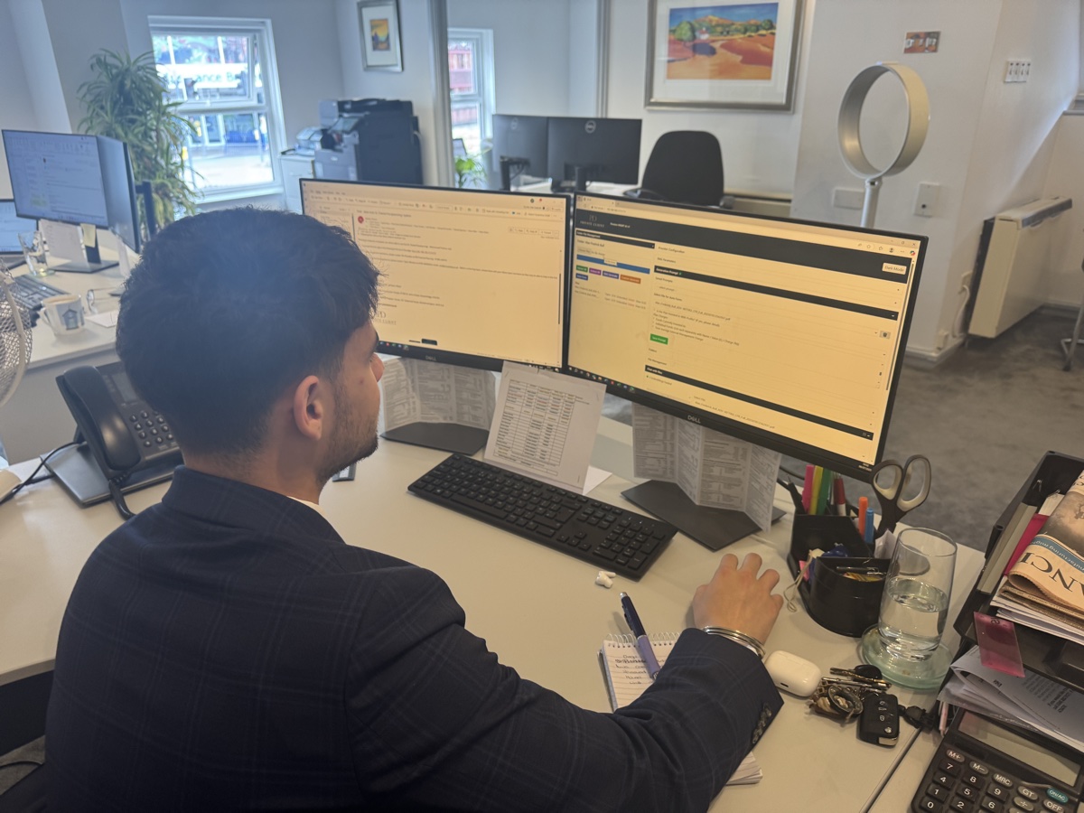 Keaton, admin staff member, working at dual monitor setup using MonAI AI-powered document processing system in bright UK office